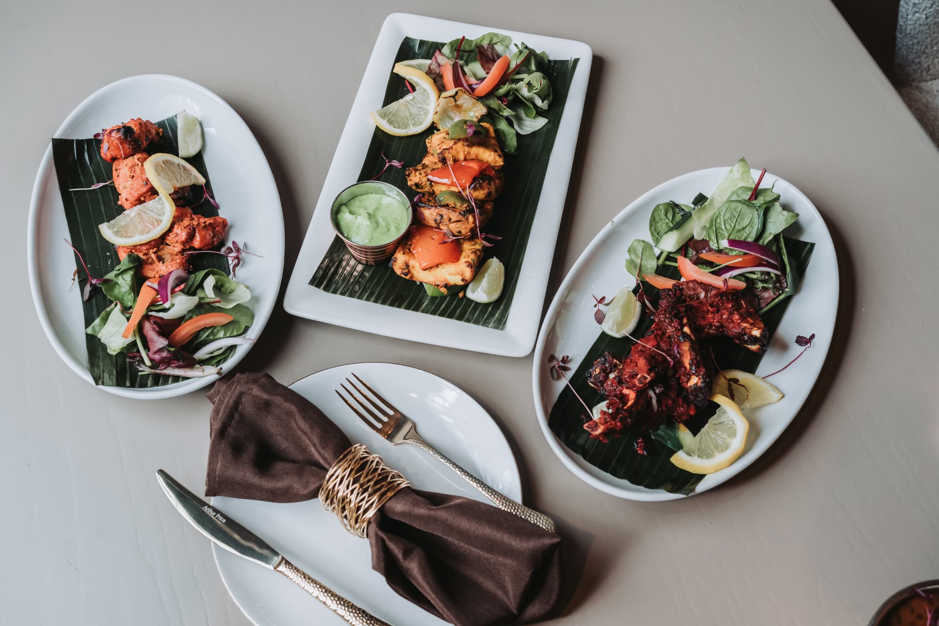 Anaya tandoori dishes laid out with gold cutlery and a brown napkin