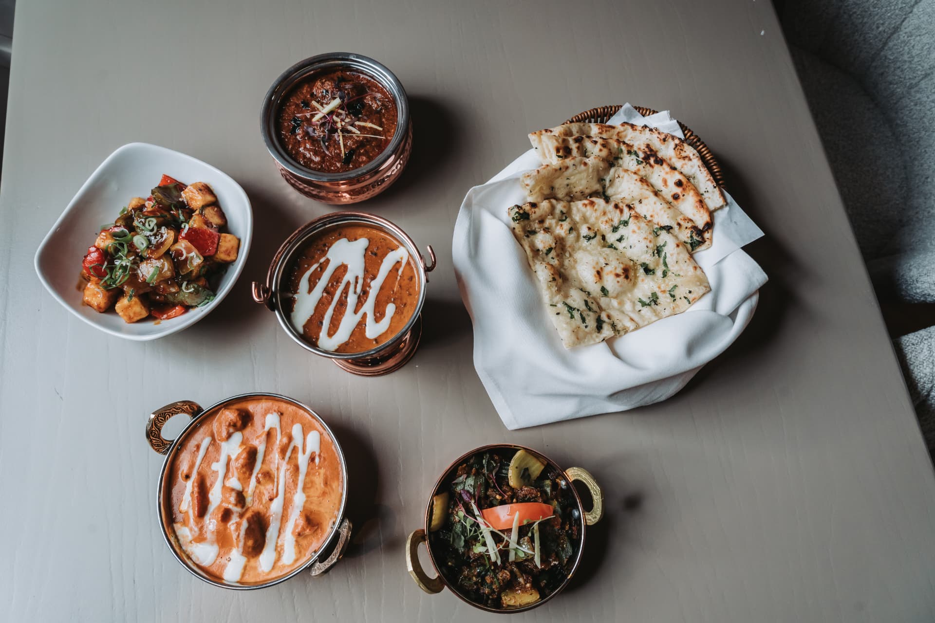 Overhead flat-lay of Anaya curries, paneer and naan