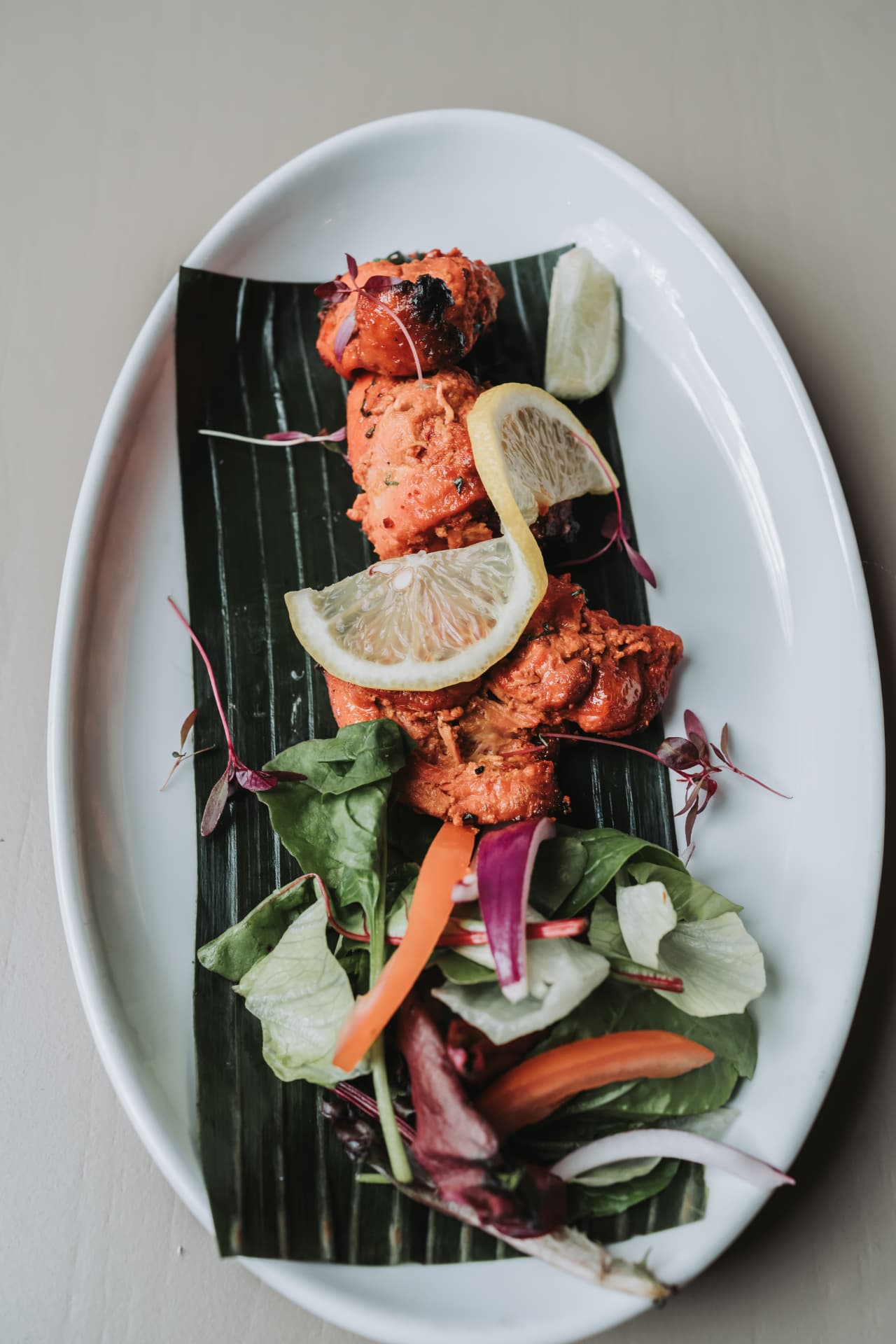 Tandoori chicken on a banana leaf with lemon and salad at Anaya