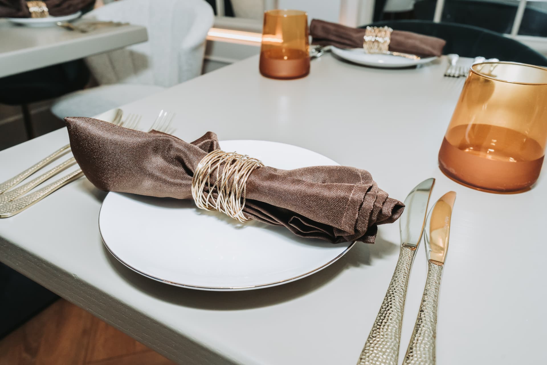 A formal table setting with gold cutlery and amber glass at Anaya