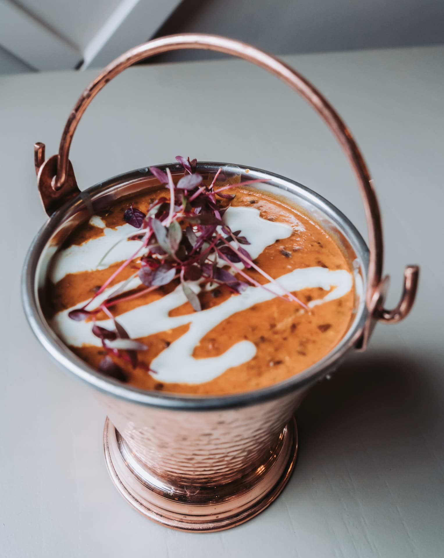Anaya curry served in a copper pot with cream and microgreens